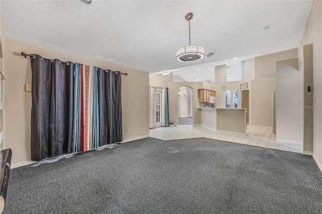 unfurnished living room featuring a textured ceiling and light colored carpet