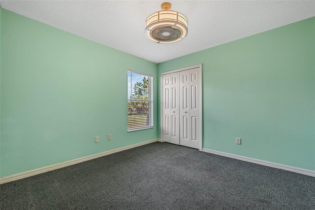 unfurnished room with dark carpet and a textured ceiling