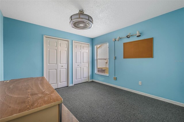 unfurnished bedroom featuring a textured ceiling, carpet, and two closets