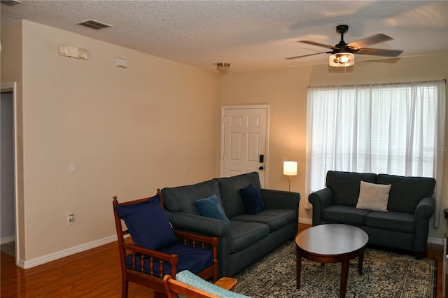 living room featuring a textured ceiling, dark wood-type flooring, and ceiling fan