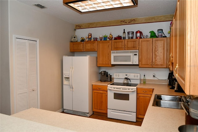 kitchen featuring a textured ceiling, sink, and white appliances