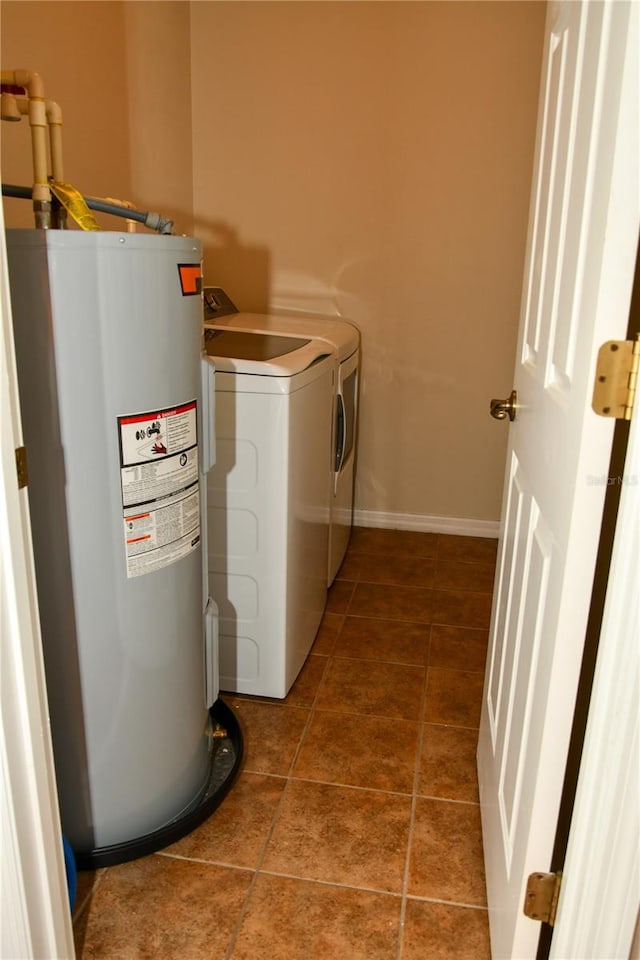 laundry room with water heater, washer and clothes dryer, and dark tile patterned floors