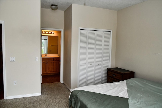 bedroom featuring a textured ceiling, a closet, ensuite bathroom, and carpet