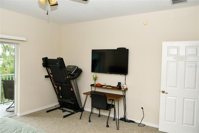 exercise area featuring a textured ceiling, ceiling fan, and light colored carpet