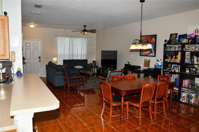 dining space with dark tile patterned floors, ceiling fan, and a textured ceiling