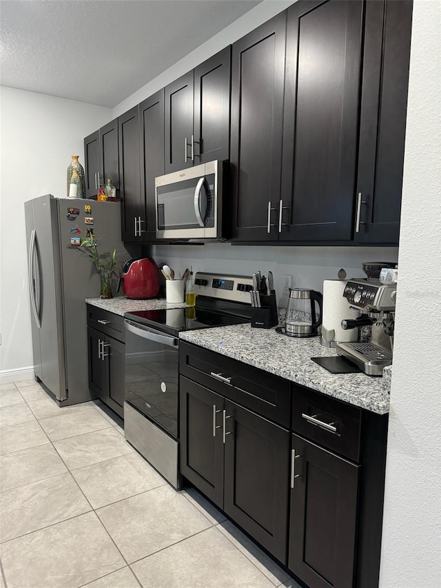 kitchen featuring light stone counters, a textured ceiling, appliances with stainless steel finishes, and light tile patterned floors