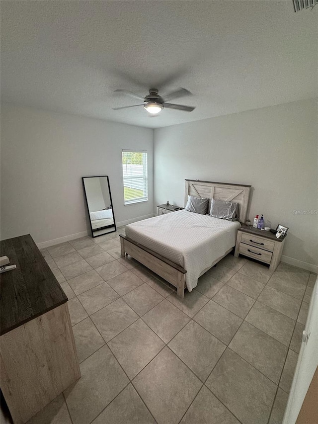 bedroom featuring ceiling fan, a textured ceiling, and light tile patterned floors