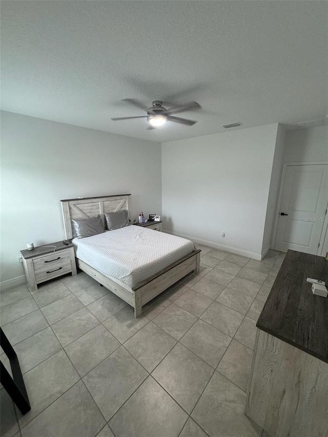 tiled bedroom with ceiling fan and a textured ceiling