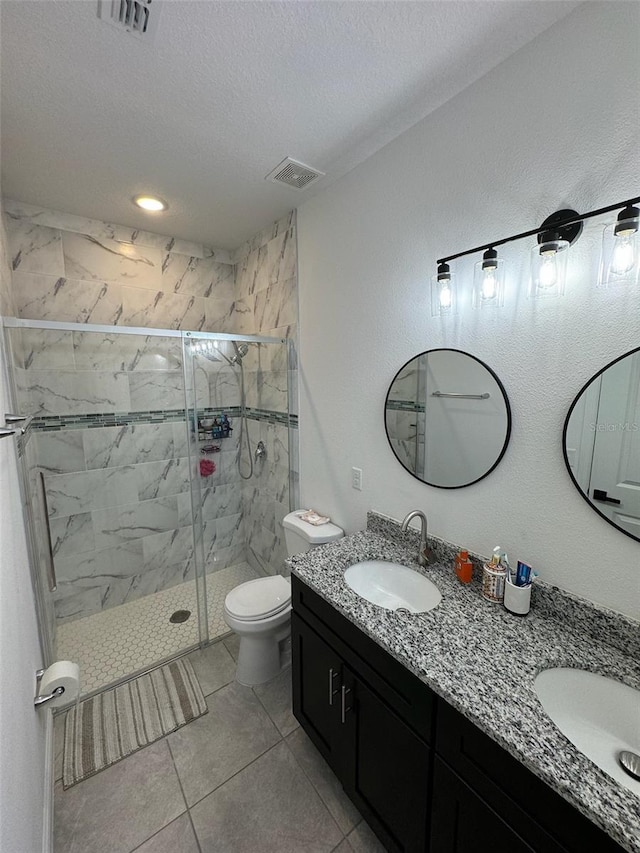 bathroom featuring a textured ceiling, walk in shower, tile patterned floors, vanity, and toilet