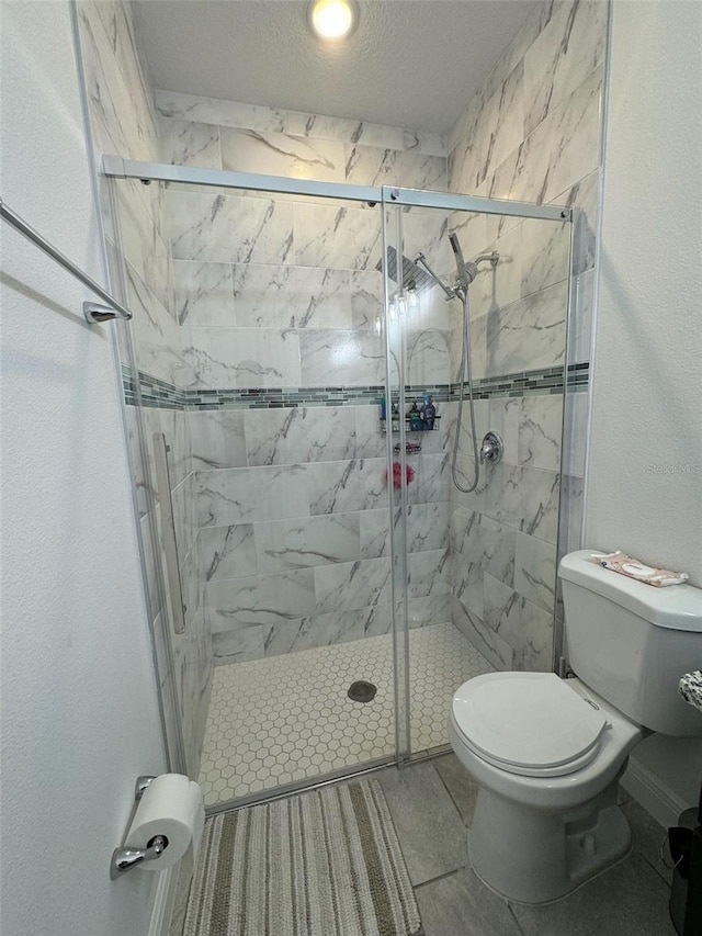 bathroom with a textured ceiling, toilet, an enclosed shower, and tile patterned floors