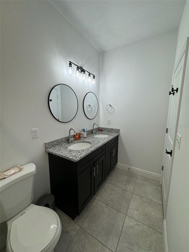 bathroom with tile patterned floors, a textured ceiling, vanity, and toilet