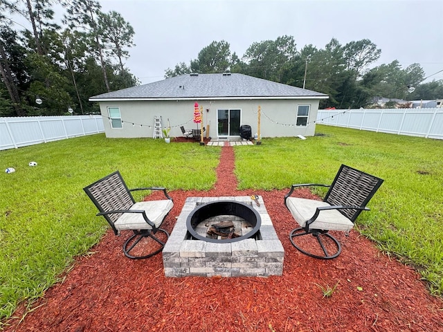 rear view of property with a yard and an outdoor fire pit