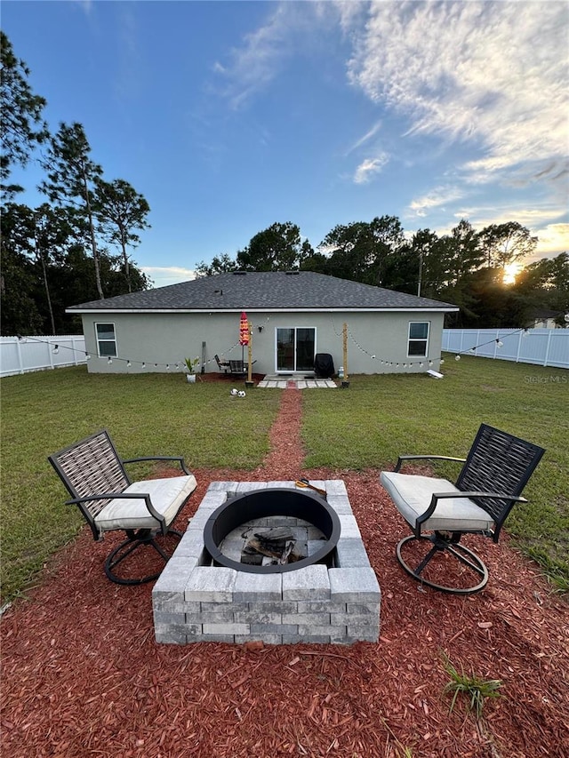 back house at dusk featuring a yard, an outdoor fire pit, and a patio area