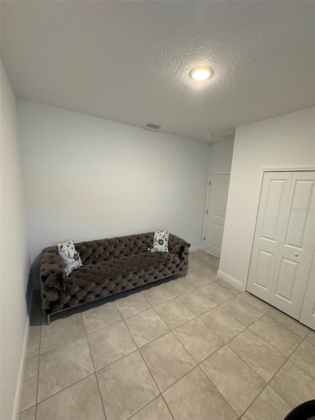 living area featuring a textured ceiling and light tile patterned flooring