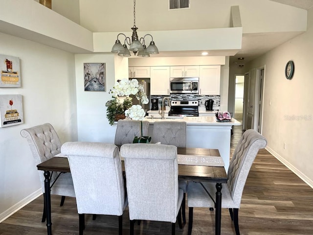 dining area with dark hardwood / wood-style flooring, sink, and an inviting chandelier