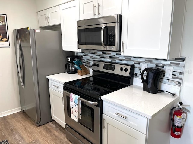 kitchen featuring light stone countertops, appliances with stainless steel finishes, tasteful backsplash, light hardwood / wood-style floors, and white cabinetry