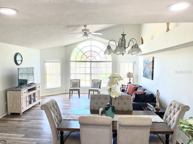 dining space with a textured ceiling, ceiling fan with notable chandelier, dark hardwood / wood-style floors, and lofted ceiling