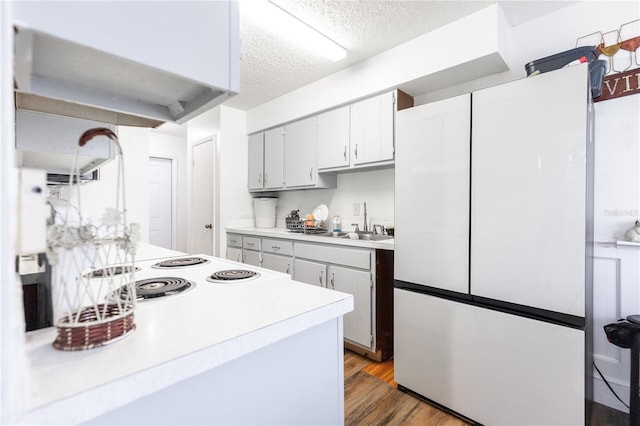 kitchen featuring wood-type flooring, white cabinetry, a textured ceiling, and white fridge