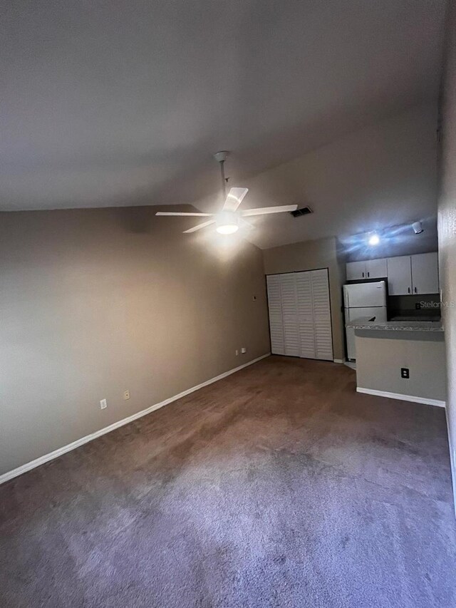 unfurnished living room with lofted ceiling, dark colored carpet, and ceiling fan