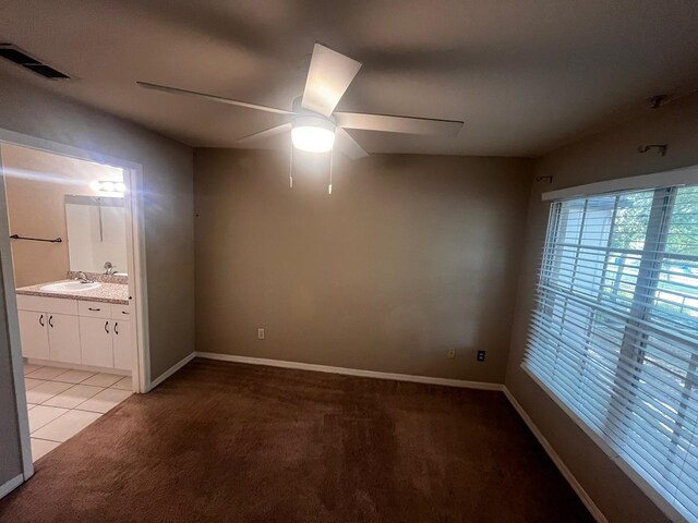 interior space with connected bathroom, light carpet, ceiling fan, and sink