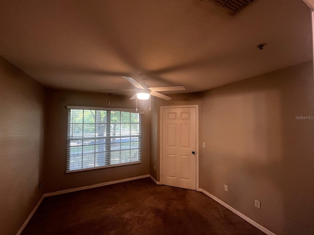 unfurnished room featuring dark carpet and ceiling fan