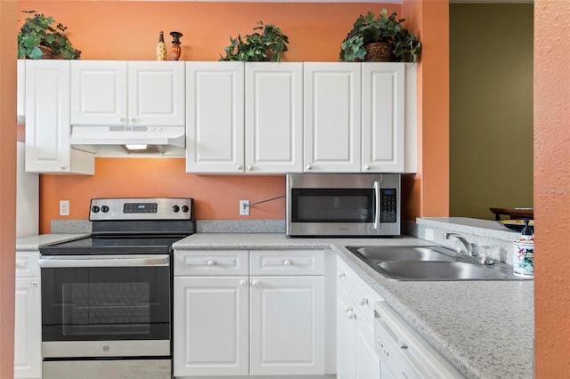 kitchen with light stone countertops, white cabinetry, sink, and stainless steel appliances