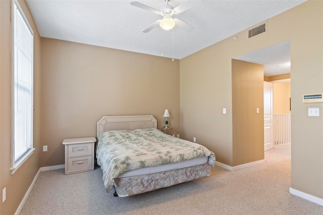 bedroom with a textured ceiling, ceiling fan, and light colored carpet