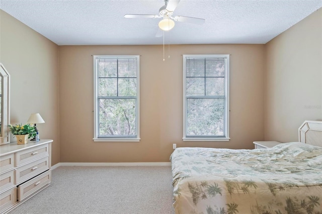 bedroom featuring ceiling fan, light colored carpet, and a textured ceiling