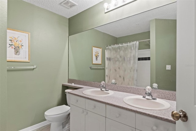 bathroom with a textured ceiling, vanity, toilet, and walk in shower