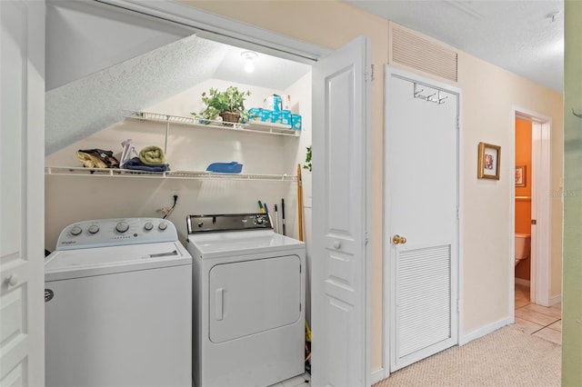 washroom featuring washing machine and clothes dryer, a textured ceiling, and light carpet