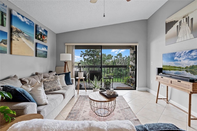 living room with vaulted ceiling, ceiling fan, light tile patterned flooring, and a textured ceiling