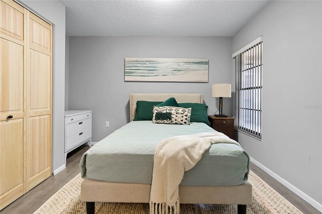 bedroom with a textured ceiling, dark wood-type flooring, and a closet