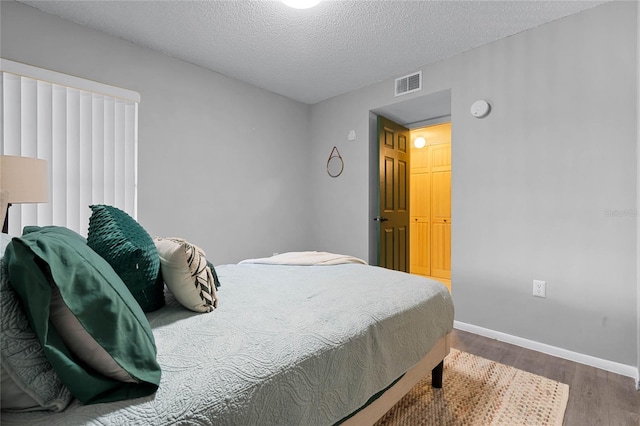 bedroom with a textured ceiling, a closet, and dark hardwood / wood-style floors