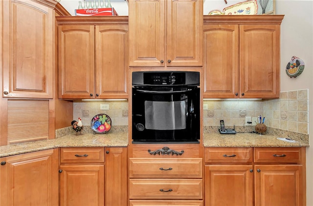 kitchen featuring backsplash, light stone countertops, and oven