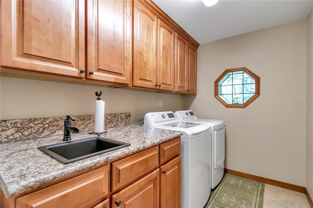 washroom with cabinets, washer and clothes dryer, and sink