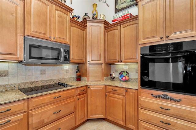 kitchen with light stone countertops, backsplash, and black appliances