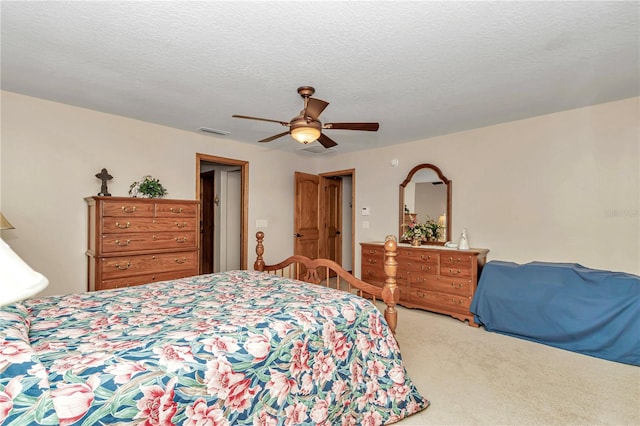 bedroom with ceiling fan, light colored carpet, and a textured ceiling