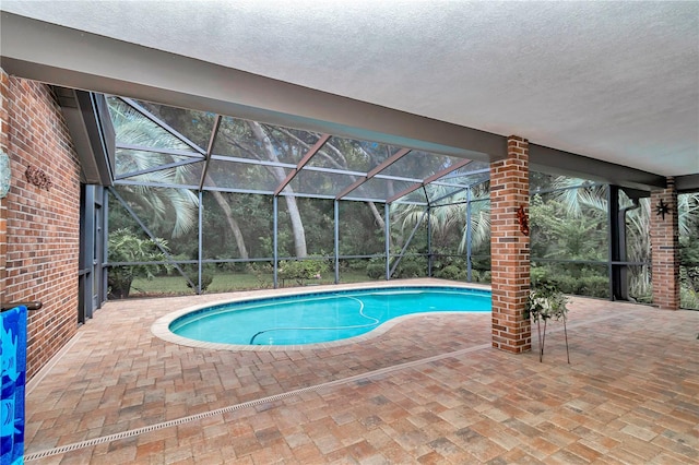 view of swimming pool with glass enclosure and a patio