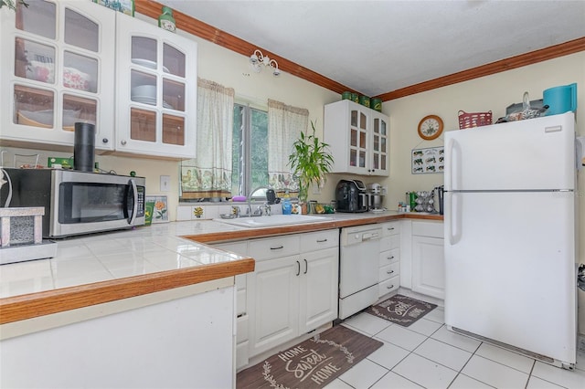 kitchen featuring white cabinets, tile countertops, ornamental molding, and white appliances