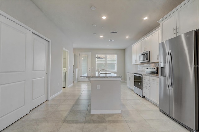 kitchen featuring light stone counters, light tile patterned flooring, an island with sink, white cabinets, and appliances with stainless steel finishes