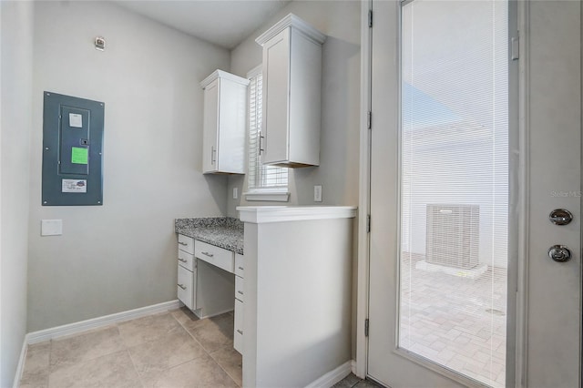 interior space with white cabinetry, electric panel, and light tile patterned floors