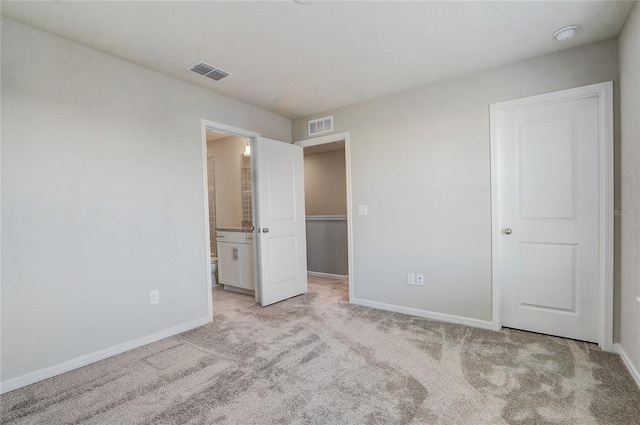 unfurnished bedroom featuring light carpet and connected bathroom