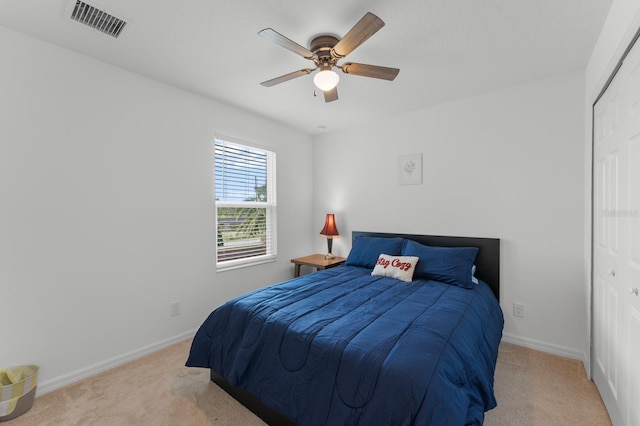 bedroom featuring ceiling fan, light colored carpet, and a closet