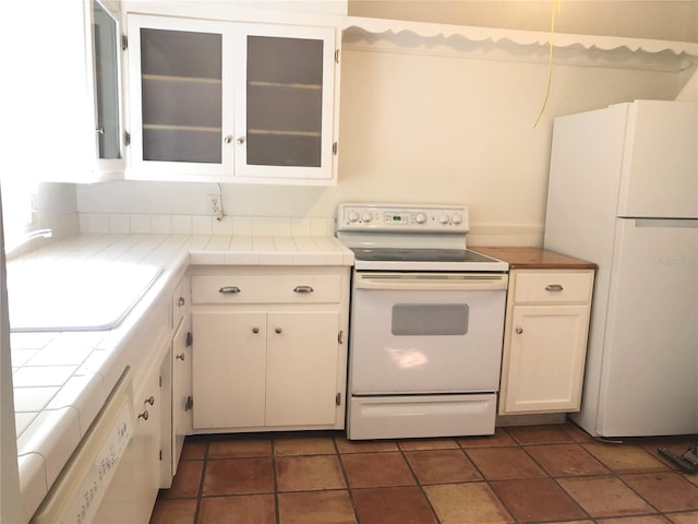 kitchen with white appliances, white cabinets, and tile countertops