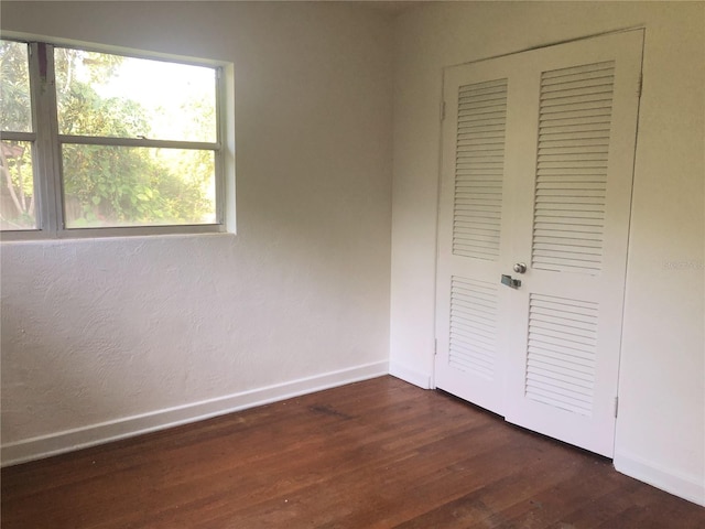 unfurnished bedroom with a closet and dark wood-type flooring