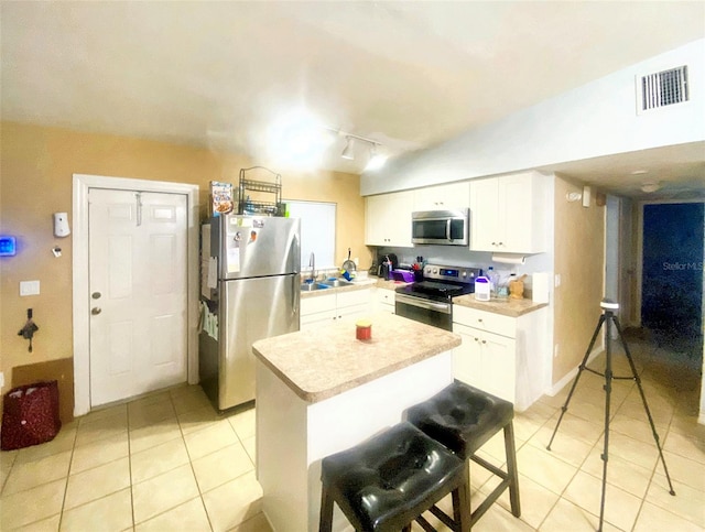 kitchen with a kitchen bar, sink, white cabinets, and appliances with stainless steel finishes