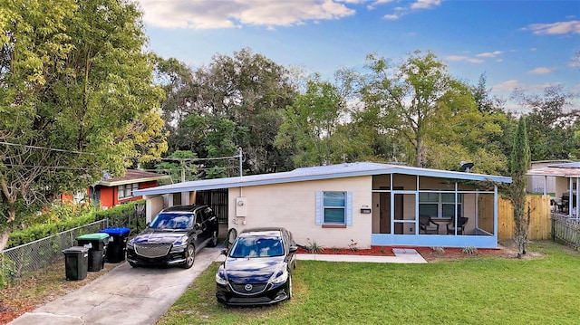 view of front facade featuring a front lawn, a carport, and a sunroom