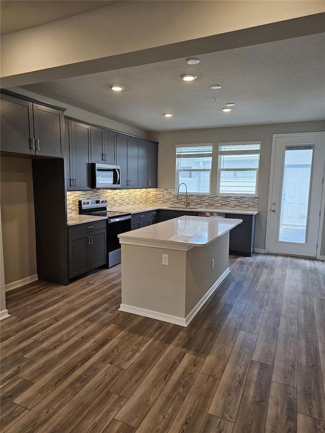 kitchen with appliances with stainless steel finishes, a center island, and dark hardwood / wood-style floors