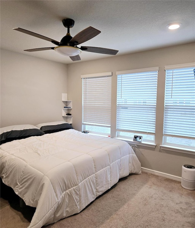 bedroom with light carpet, ceiling fan, and a textured ceiling