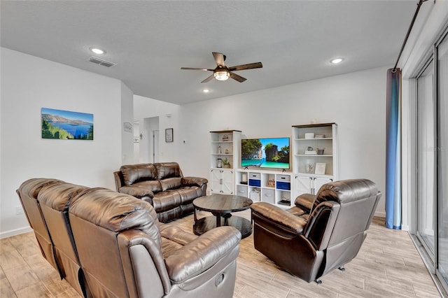 living room featuring ceiling fan, a textured ceiling, and light wood-type flooring